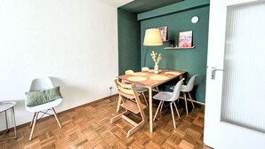 Un comedor con una mesa de madera, sillas, una lámpara y un florero con flores.