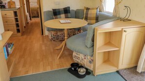 Een gezellig interieur van een camper met een bank, een eettafeltje en een dierenbedje.