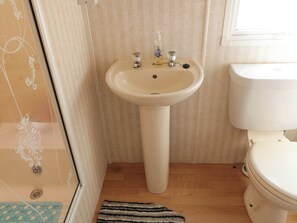 Une salle de bain avec un lavabo blanc, des toilettes et un espace douche.