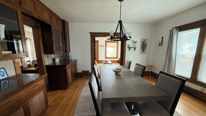 A spacious kitchen with wooden cabinets, a large dining table, and a chandelier. - Cozy Farmhouse Getaway 10 min from Lost Island and Casino (La Porte City)