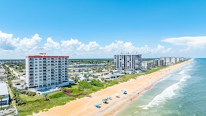Un hôtel situé sur la côte, composé de plusieurs immeubles de grande hauteur, avec une plage de sable et une vue sur l’océan.