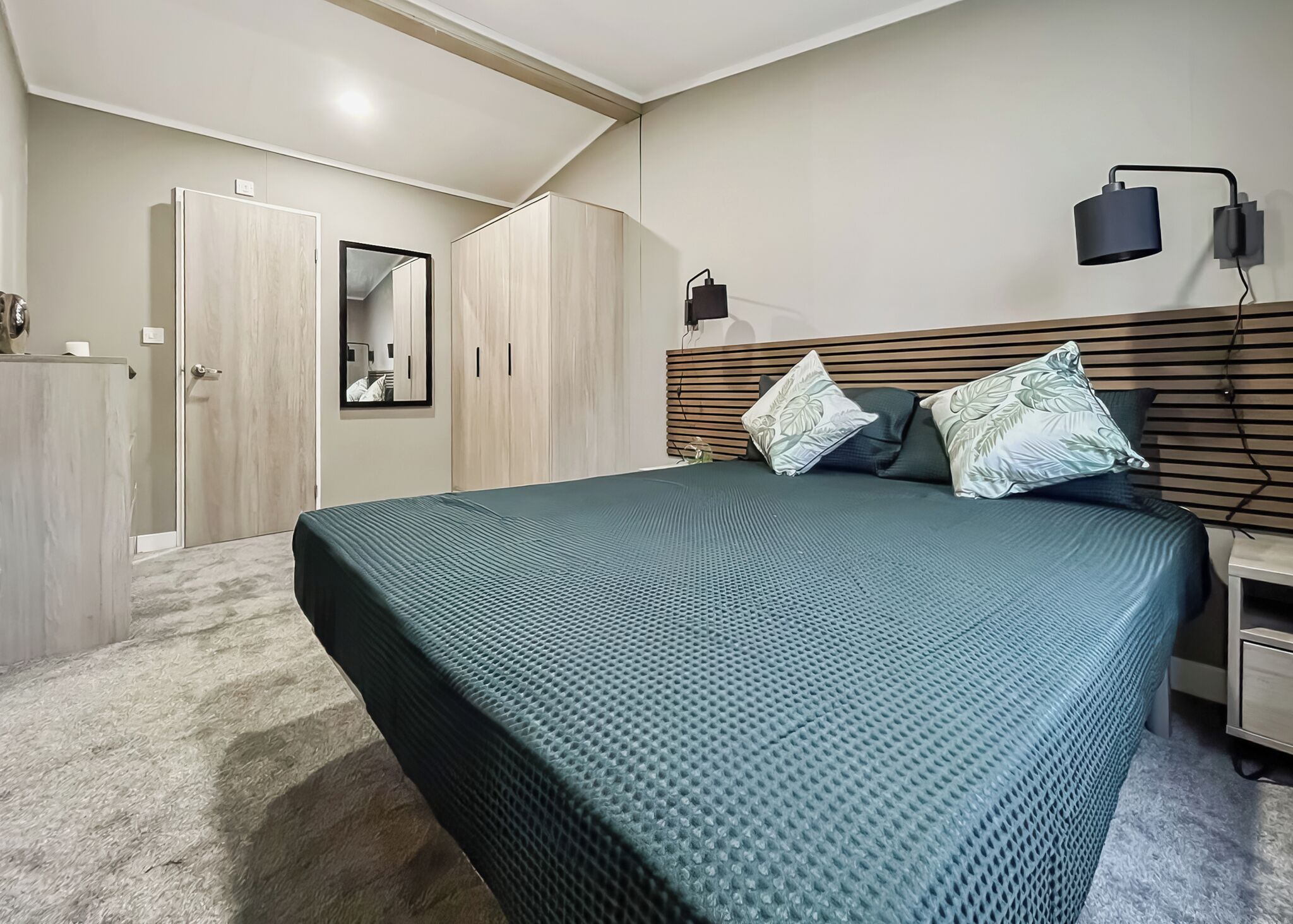 Une chambre à coucher avec un lit, une armoire, un miroir et une table de chevet.