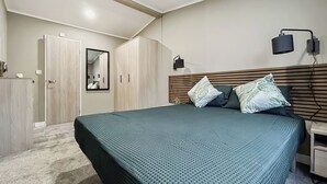 Une chambre à coucher avec un lit, une armoire, un miroir et une table de chevet.