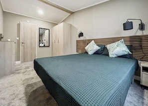 Ein Schlafzimmer mit Bett, Kleiderschrank, Spiegel und Nachttisch.