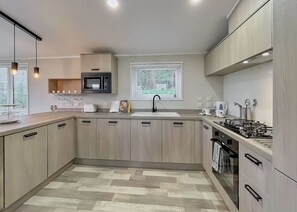 A modern kitchen with a microwave, sink, and stove. - Superior Lodge 2 Bed (Tunstall, Richmond)