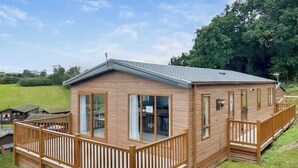 Une cabane en bois dotée d’un balcon, de grandes fenêtres et d’un toit plat.