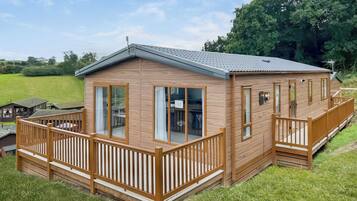 Une cabane en bois dotée d’un balcon, de grandes fenêtres et d’un toit plat.
