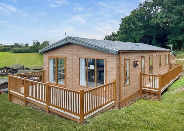A wooden cabin with a balcony, large windows, and a flat roof.