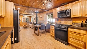 Interior de una cabaña de madera con cocina, comedor y sala de estar.