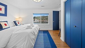 A bedroom with a bed, a window with a view, a blue door, and a ceiling light. - The Boathouse Large Modern Renovated Waterfront Home with Decks and Docks (Coeur d'Alene)