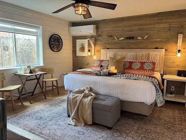 Une chambre confortable avec un lit, des tables de chevet, une petite table et des chaises.
