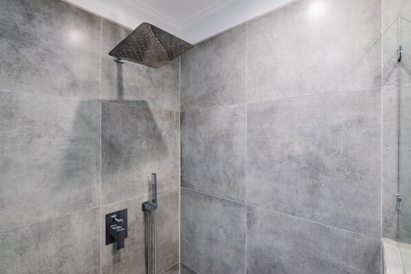 Une douche moderne dotée d’un pommeau de douche carré et d’un flexible de douche.