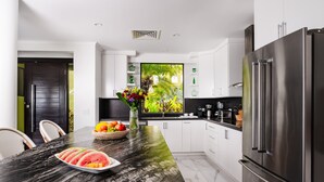 Una cocina moderna con una isla de mármol, electrodomésticos de acero inoxidable y vistas a zonas verdes.