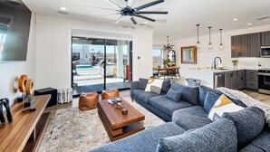 A modern living room with a grey sofa, wooden coffee table, and a dining area with a white table and chairs. - Villa Solara – Ultimate Backyard & Gameroom (Lake Havasu City)