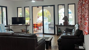 A living room with a sofa, a TV, and a ceiling fan. There are large windows and a view of the outside. - Villa El Tule
Beautiful home in the Corridor Area.
Minutes to Chileno Bay (Cabo San Lucas)