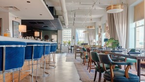 Un restaurante moderno con taburetes azules, mesas de madera y sillas verdes.