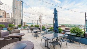 Una terraza en la azotea con mobiliario exterior, luces colgantes y vistas de la ciudad.