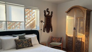 Un dormitorio con una cama grande, un armario de madera, una silla y una escultura de animal montada en la pared.