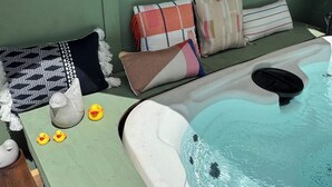 Un jacuzzi con cubierta de madera, rodeado de varios cojines y una decoración con forma de pato.