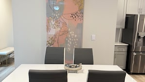 A modern dining area with a white table, black chairs, and a decorative wall piece. - Charming 3-bedroom townhome with loft, WiFi and AC in peaceful Lawrenceville (Lawrenceville)
