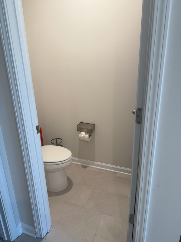 A small bathroom with a toilet, a toilet paper holder, and a door.