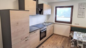 Eine kleine Küche mit Einbauofen, Spüle und Holzschränken.