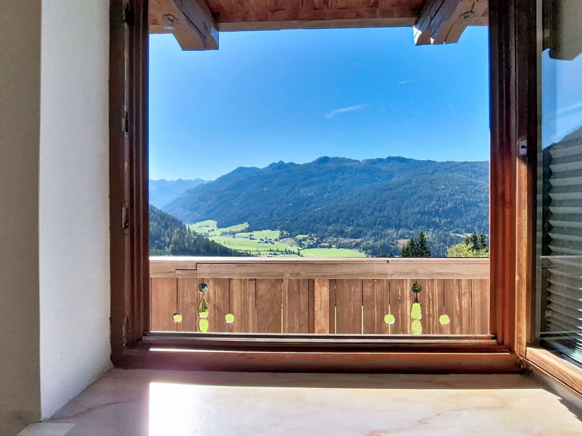 Un balcón con baranda de madera y vista a un paisaje montañoso.