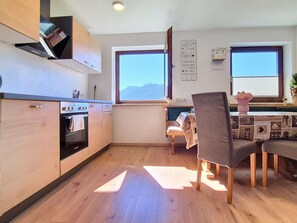 A modern kitchen with wooden cabinets, a built-in oven, and a dining area with a table and chairs.