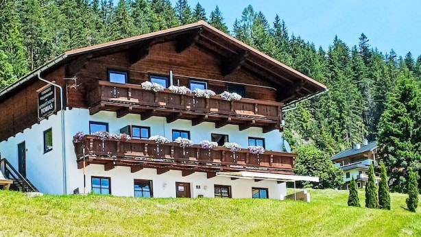 Ein mehrgeschossiges Gebäude mit Balkonen, umgeben von einer grünen Wiese und Bäumen.