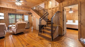 A wooden interior with a staircase, a sofa, and a bed.