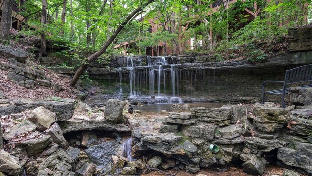 Een natuurlijke waterval, omringd door rotsen en bomen.