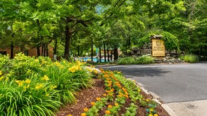A well-maintained garden with a stone sign, a paved road, and a pool in the background. - Relaxing Branson Cabin Getaway (Branson)