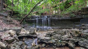 Ein natürlicher Wasserfall, umgeben von Felsen und Bäumen.
