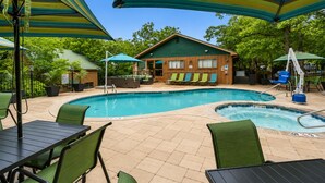 Ein Poolbereich mit Liegestühlen, Sonnenschirmen und einem Holzgebäude im Hintergrund.