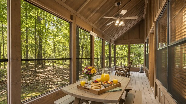 Eine Holzterrasse mit Frühstückstisch, großen Fenstern und Deckenventilator.