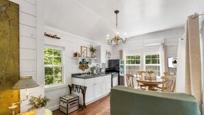 A cozy kitchen with white cabinets, a dining table, and chairs. There is a chandelier hanging from the ceiling.