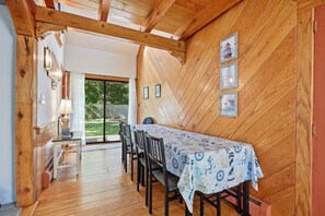 A dining area with a table set for four, wooden walls, and a view of the outdoors. - Family & Pet-Friendly Cape Escape Near Beach (Hyannis)