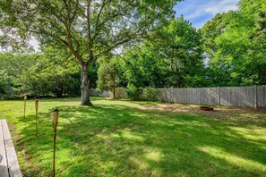 A backyard with a wooden fence, a tree, and a picnic table. - Family & Pet-Friendly Cape Escape Near Beach (Hyannis)