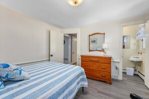 Een slaapkamer met een bed, een kaptafel en een badkamer met een wastafel en spiegel.