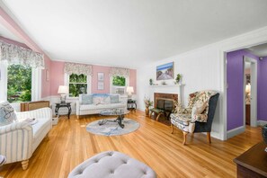 A living room with a sofa, armchairs, a fireplace, and a view of greenery outside. - Family & Pet-Friendly Cape Escape Near Beach (Hyannis)