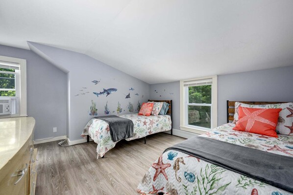 A bedroom with two beds, a window, and a wall decorated with marine life decals.