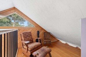 A small attic room with a sloped ceiling, wooden floor, a radiator, two chairs, and a small table. - Family & Pet-Friendly Cape Escape Near Beach (Hyannis)