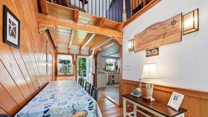 A wooden interior with a dining area, a kitchen, and a wall-mounted compass. - Family & Pet-Friendly Cape Escape Near Beach (Hyannis)