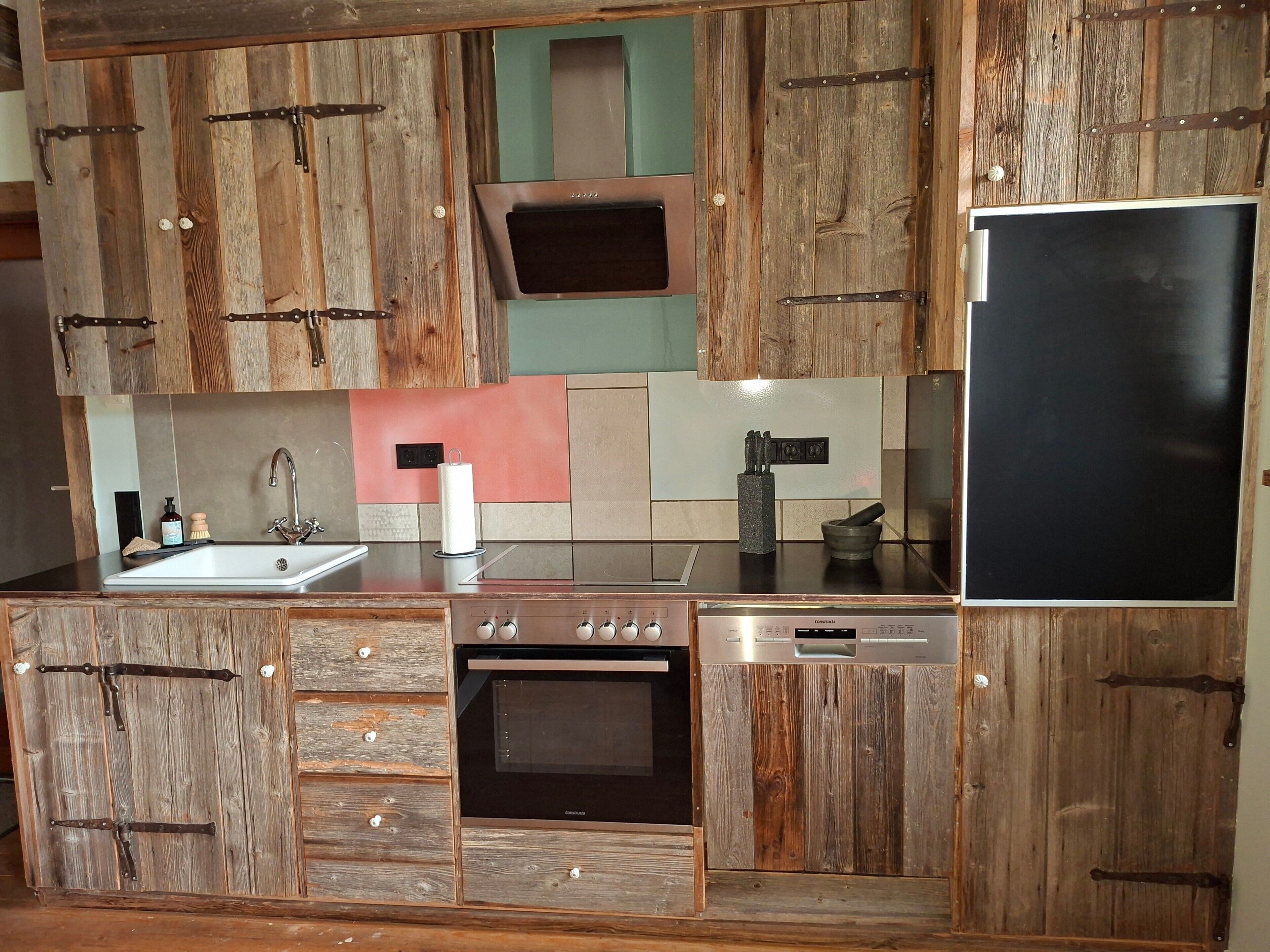 Una cocina con armarios de madera, un lavamanos de acero inoxidable, una estufa y un refrigerador.