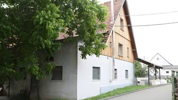Ein modernes Haus mit einem geneigten Dach, ein großer Baum davor und ein gepflasterter Auffahrt.