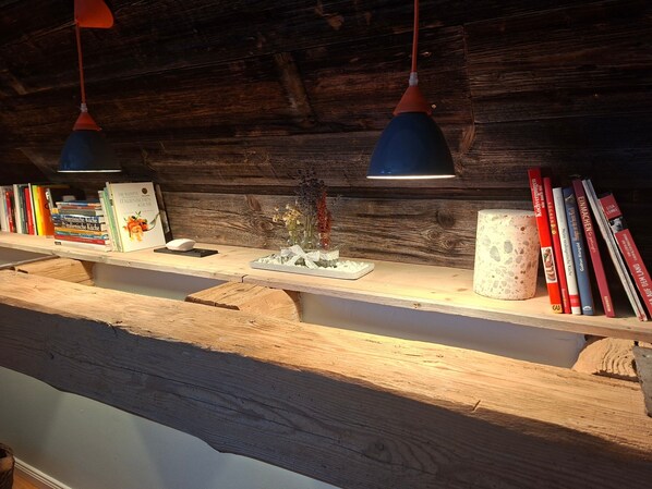 A wooden shelf with books, a small vase with flowers, and a candle holder.