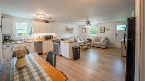 A spacious kitchen with white cabinets, a dining area with a checkered tablecloth, and a living room with a sofa and coffee table.