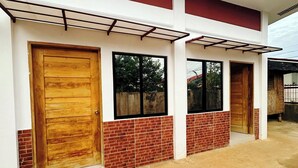 A modern building with a brick facade, large wooden doors, and a covered entrance area. - Amwani Residence - Kalikasan Homes (Puerto Princesa)