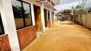 A building with a brick facade, large windows, and a covered walkway. - Amwani Residence - Kalikasan Homes (Puerto Princesa)