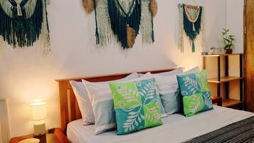 A hotel room with a bed, bedside tables, a lamp, and macramé wall hangings.